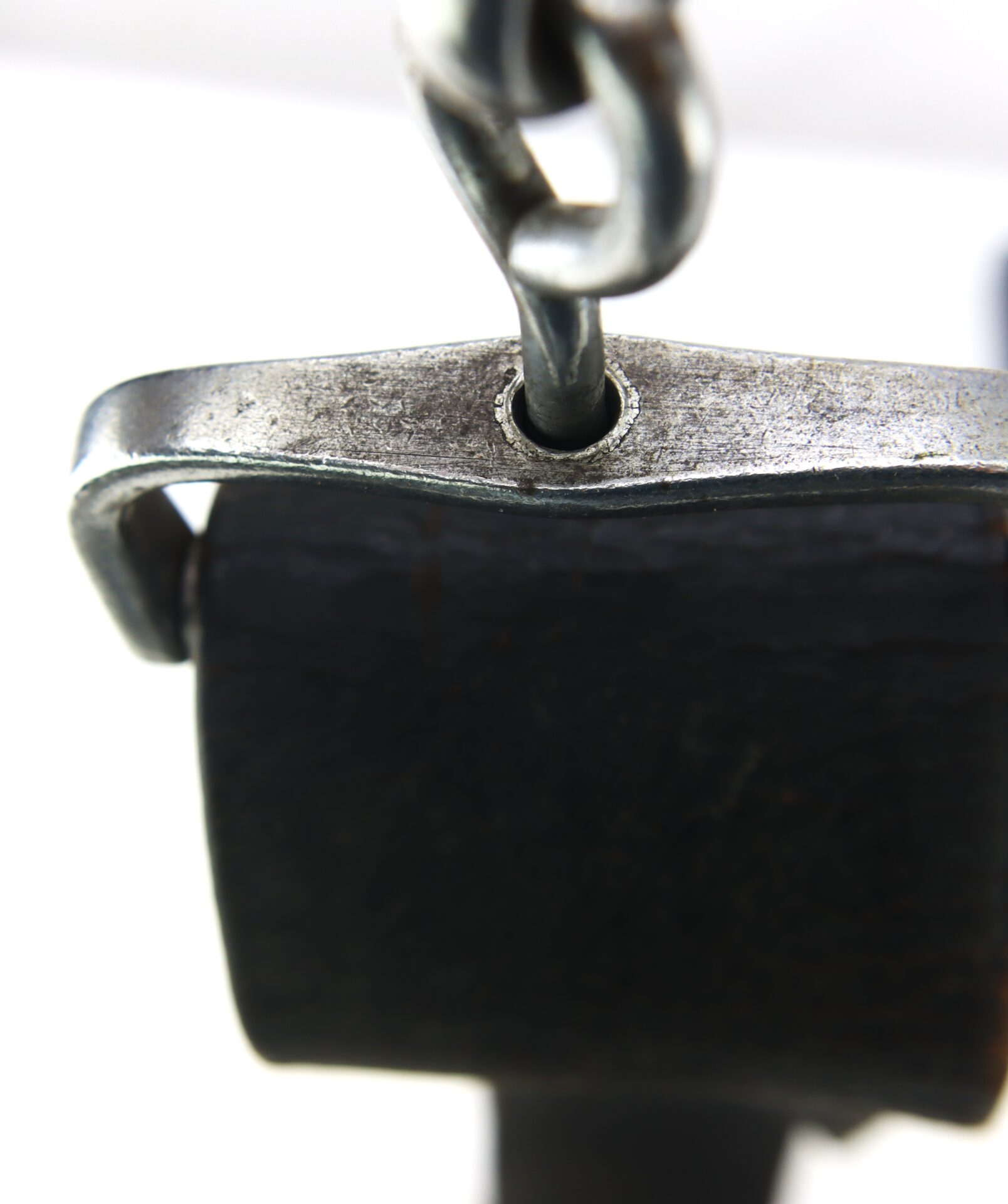 Close-up of the Cavalry Carbine Sling's metal chain link attached to a weathered black leather strap, secured by a metal loop.