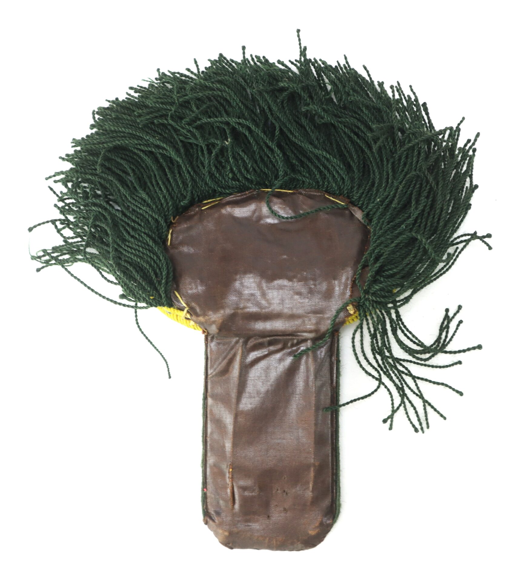 A flat, brown, paddle-shaped object with a top section covered in dense, dark green strands, resembling yarn or tassels.