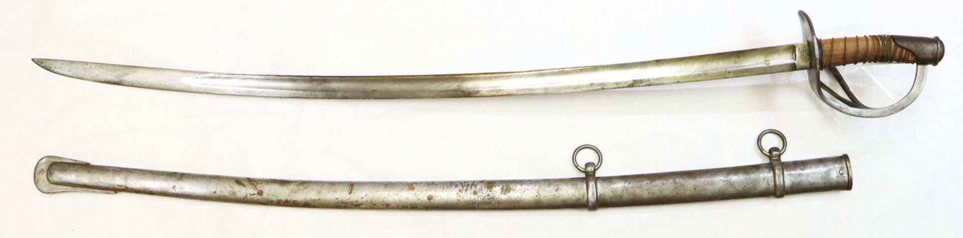 A vintage cavalry saber with a curved blade and a metal handguard, displayed above its metal scabbard with two rings.