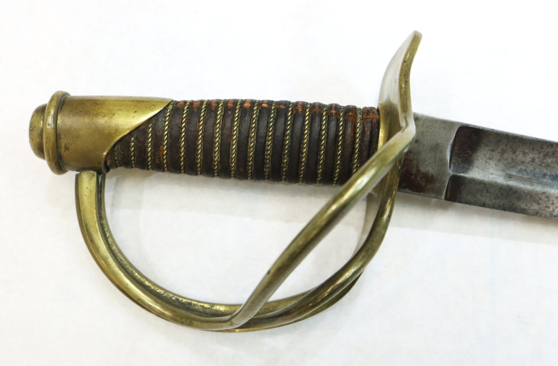 Close-up of a sword hilt with a brass guard, wire-wrapped grip, and part of a steel blade on a white background.