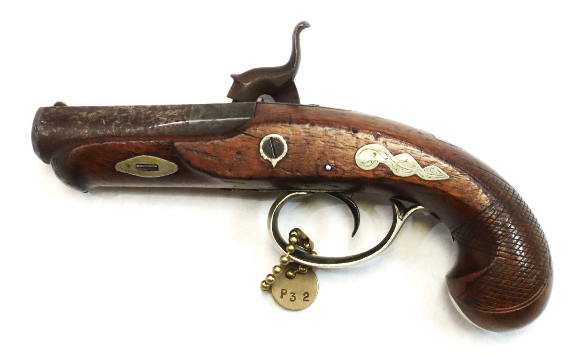 An antique flintlock pistol with a wooden handle, metal trigger, and brass tag labeled "P32" attached to the trigger guard.
