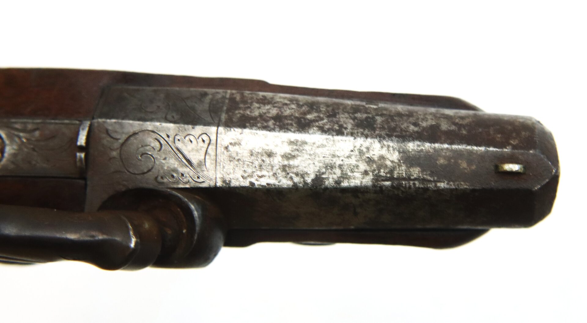 Close-up view of an antique metal firearm barrel with engraved detailing and visible wear, photographed against a white background.