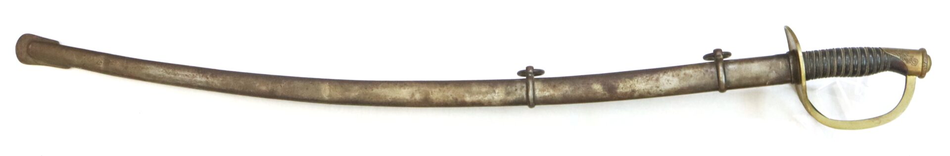 A vintage cavalry saber with a curved blade, brass handguard, and black grip, shown in its metal scabbard with two mounting rings.