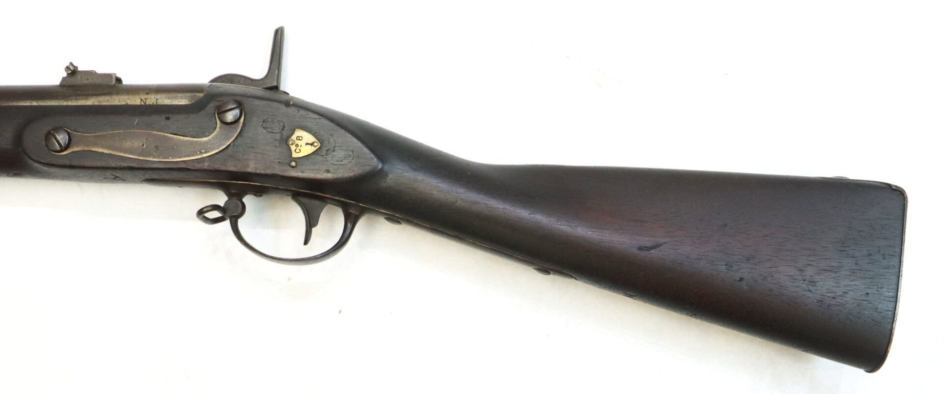 Partial view of an antique rifle showing the wooden stock, trigger, and lock mechanism against a white background.