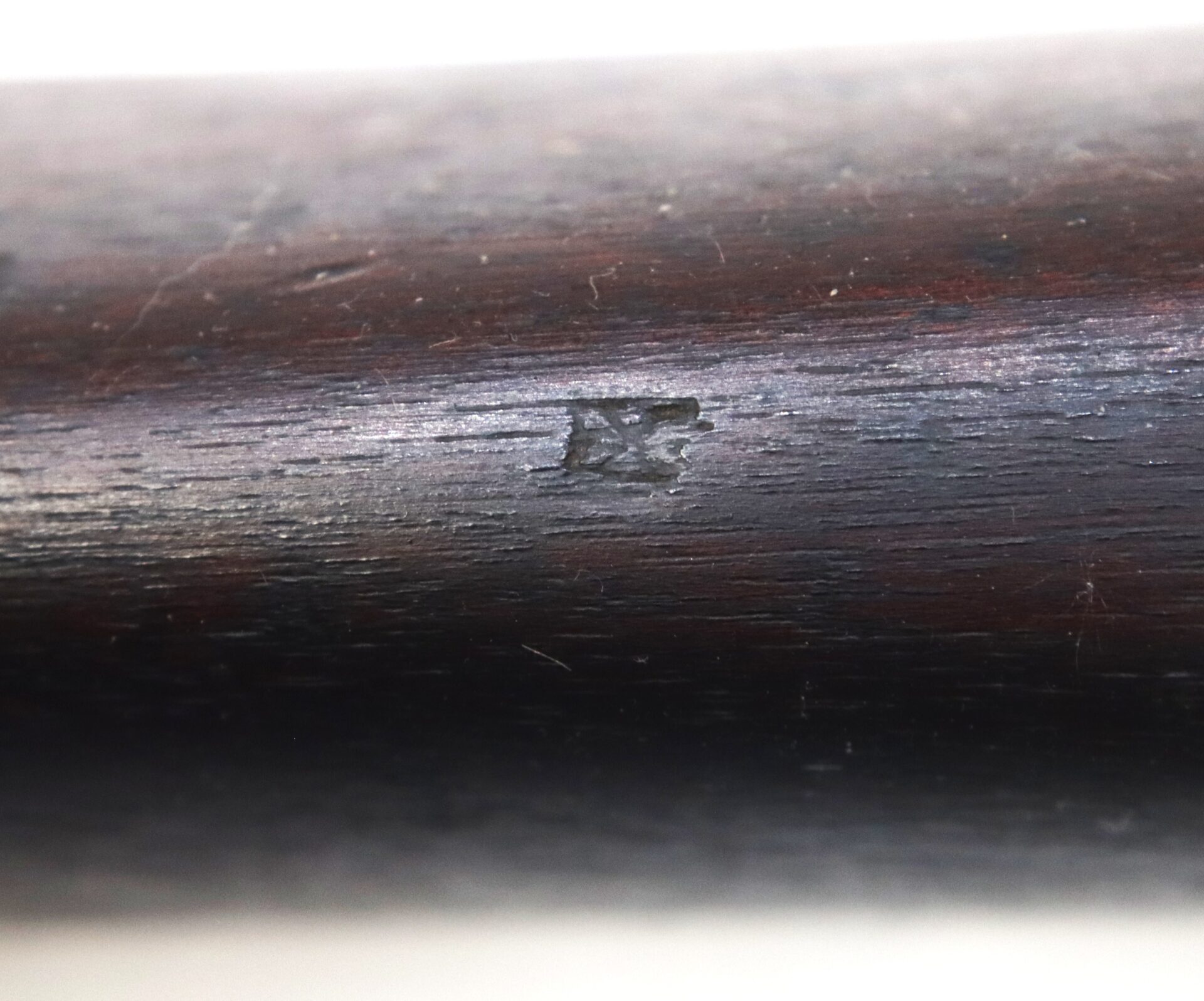 Close-up of a dark wooden surface with the engraved marking "IX" in the center.