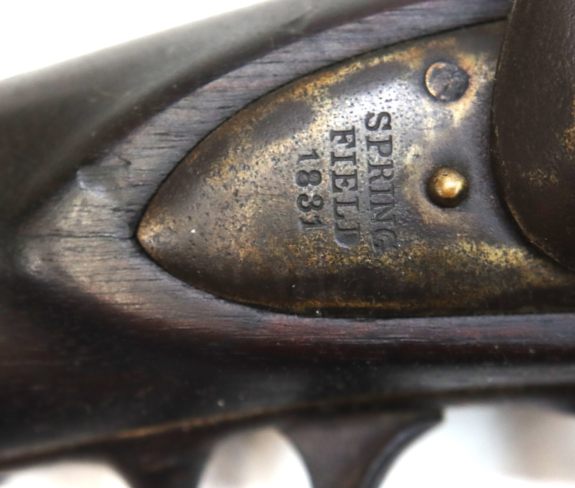Close-up of a metal plate on a firearm showing engraved text: "SPRINGFIELD 1831" with visible aging and wear on the wood and metal.