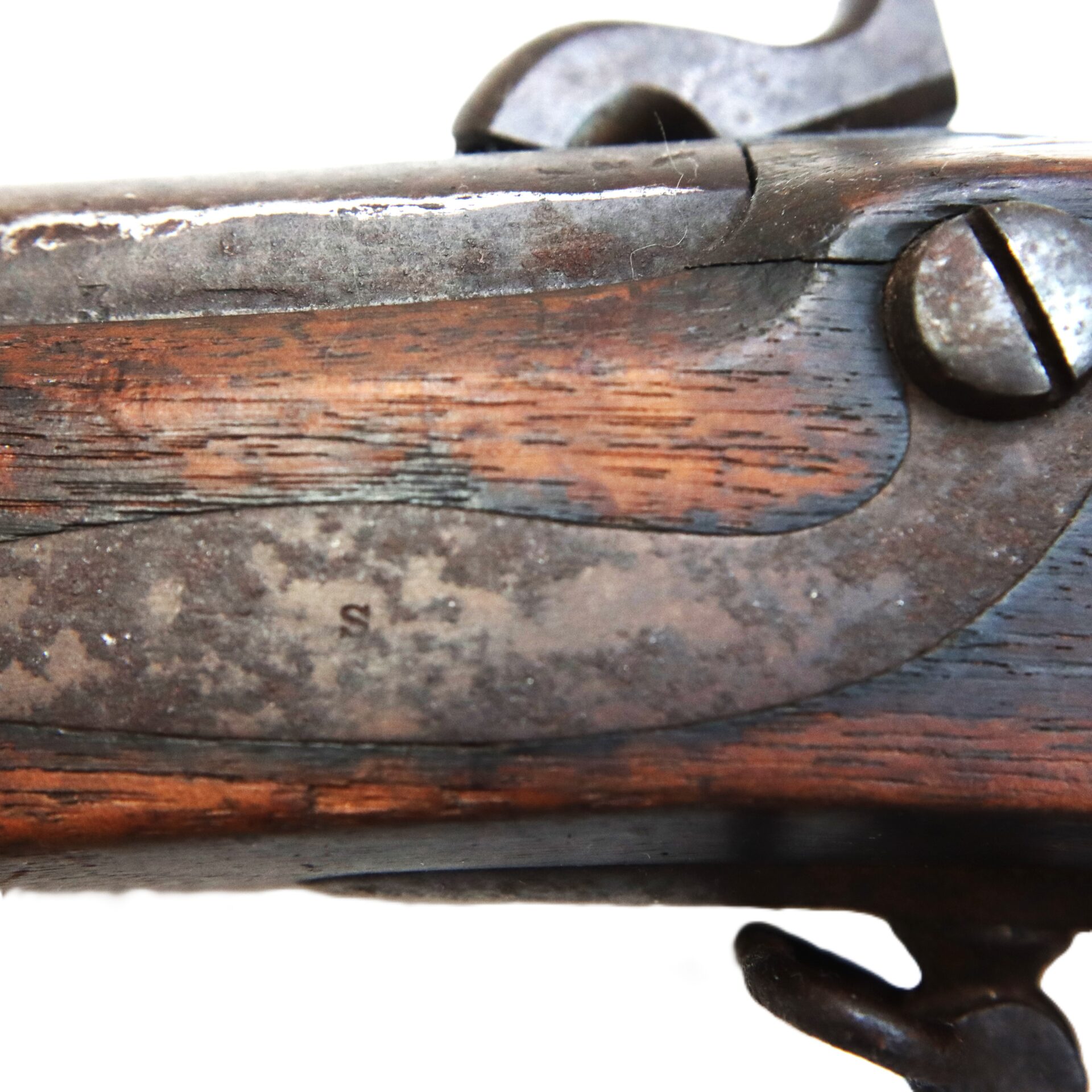 Close-up view of the metal and wooden section of an antique rifle, showing aged wood grain, rust, and metal screws against a white background.
