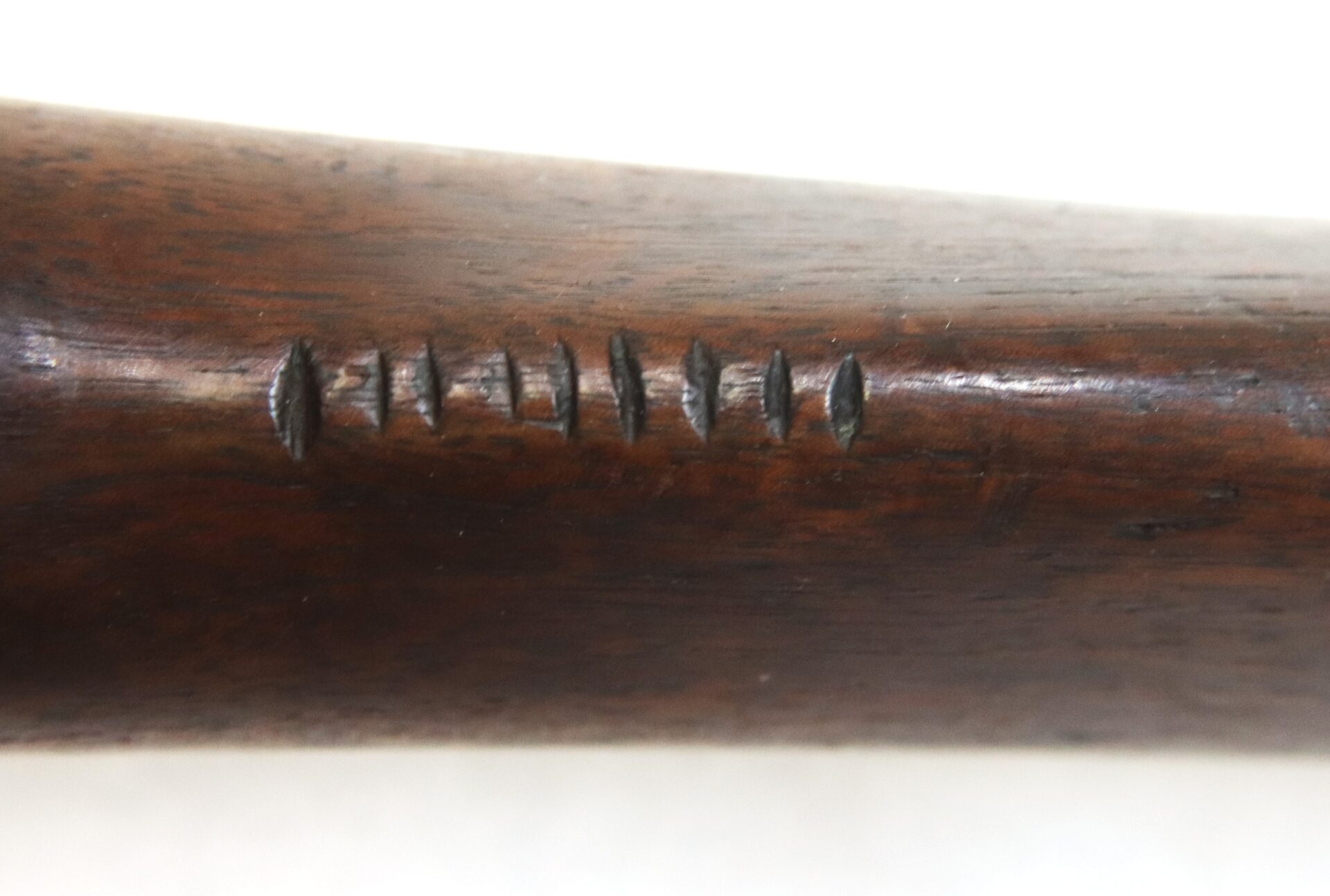 Close-up of a dark wooden surface with six small tally marks carved into it.