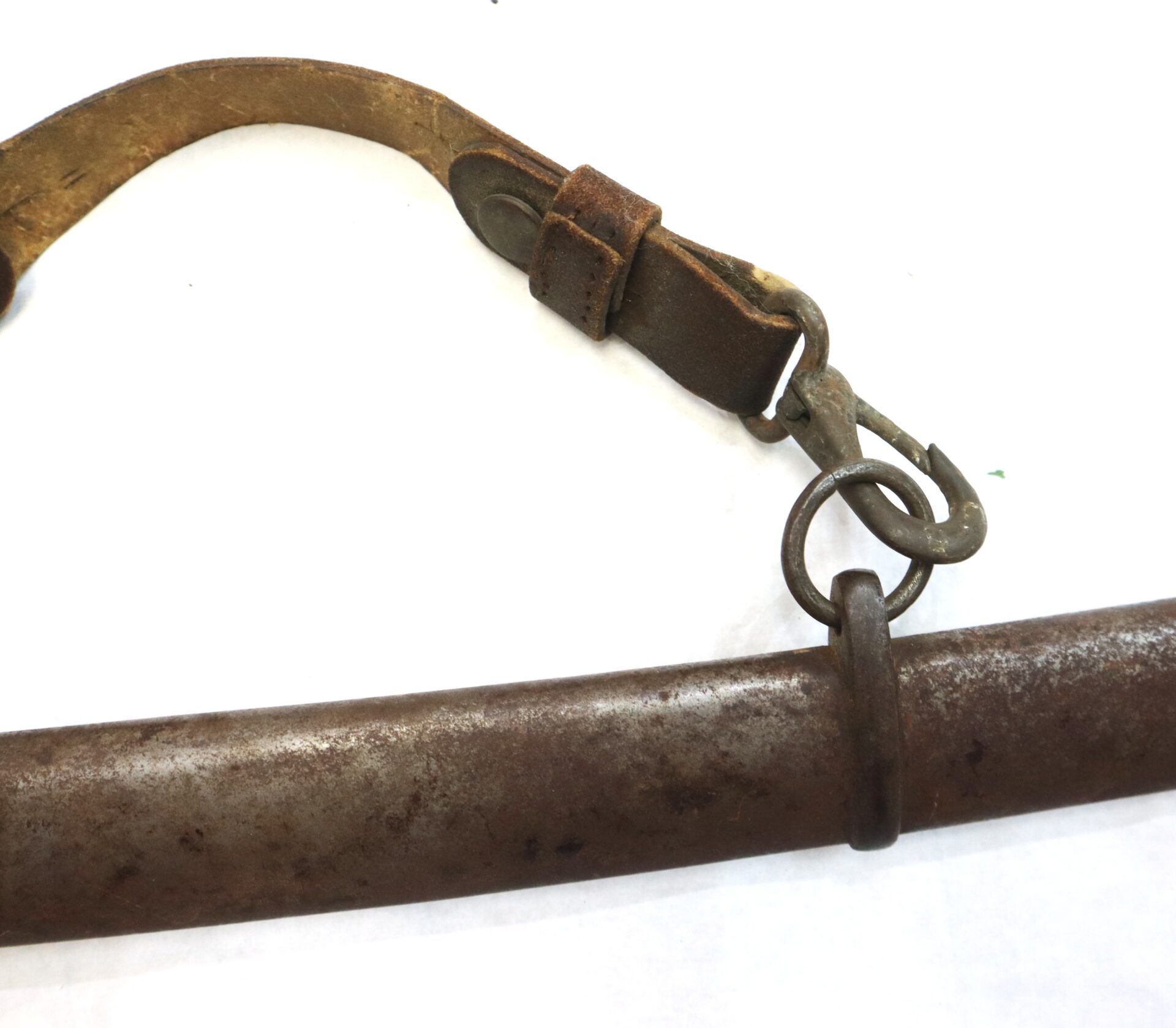A close-up of a worn leather strap with metal clasps attached to a rusted metal rod on a white background.
