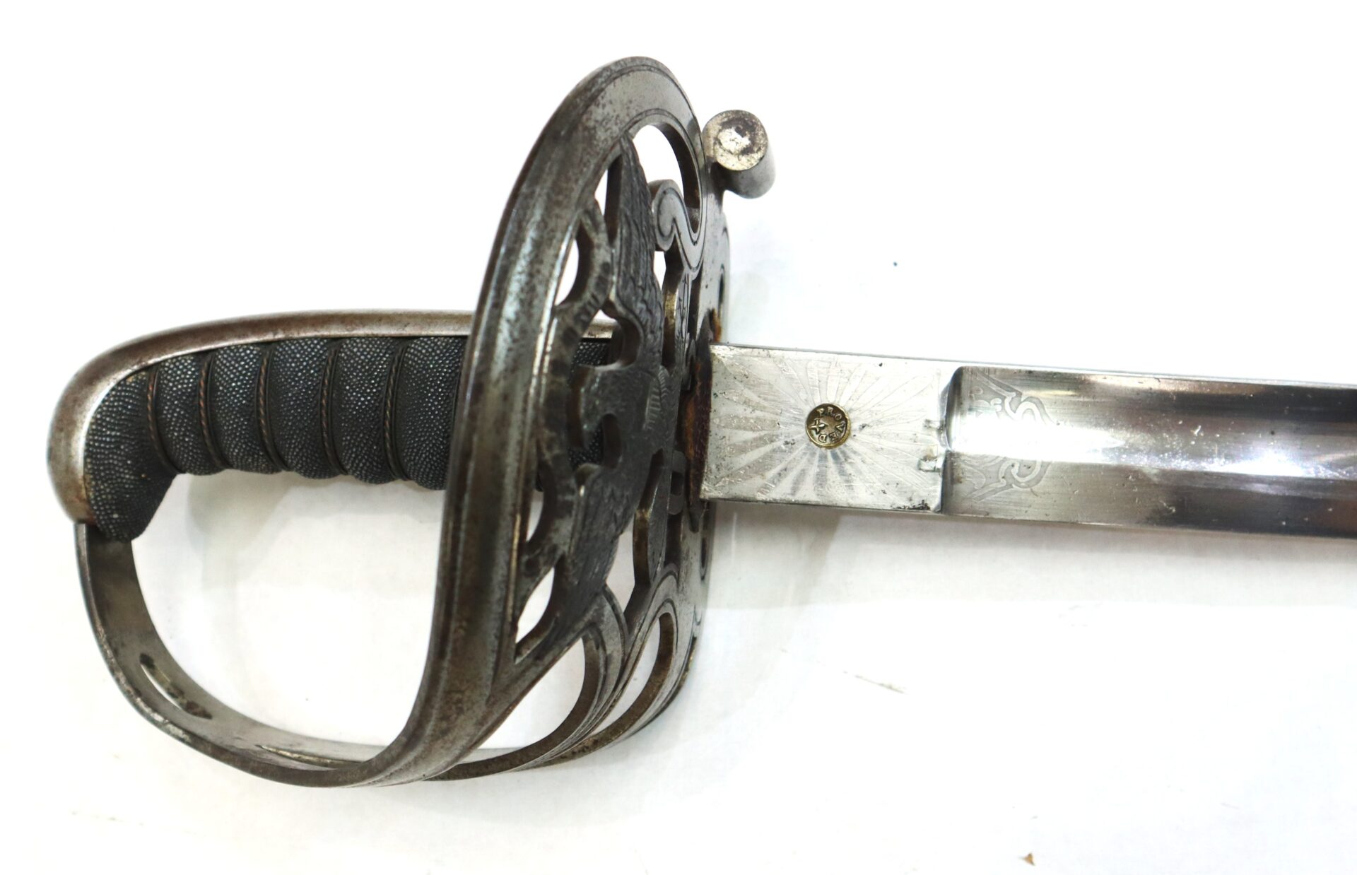 A close-up of a sword with an ornate metal handguard, a black grip, and a partially engraved blade on a white background.