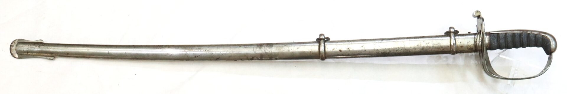 A metal cavalry saber with a curved blade, black handle, hand guard, and metal scabbard featuring two suspension rings, set on a white background.