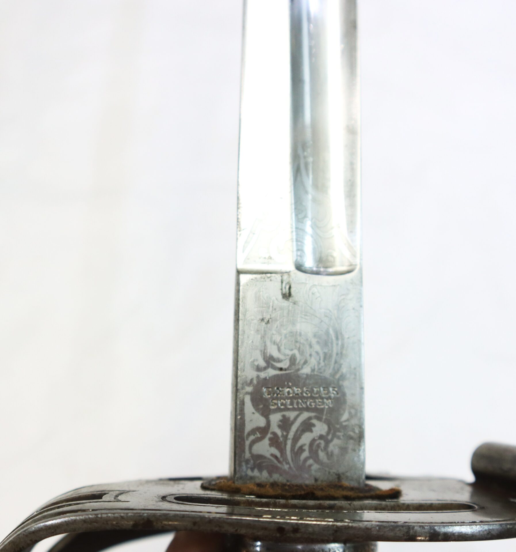 Close-up view of a sword blade with engraved patterns and the inscription "HORSTER SOLINGEN" near the hilt.