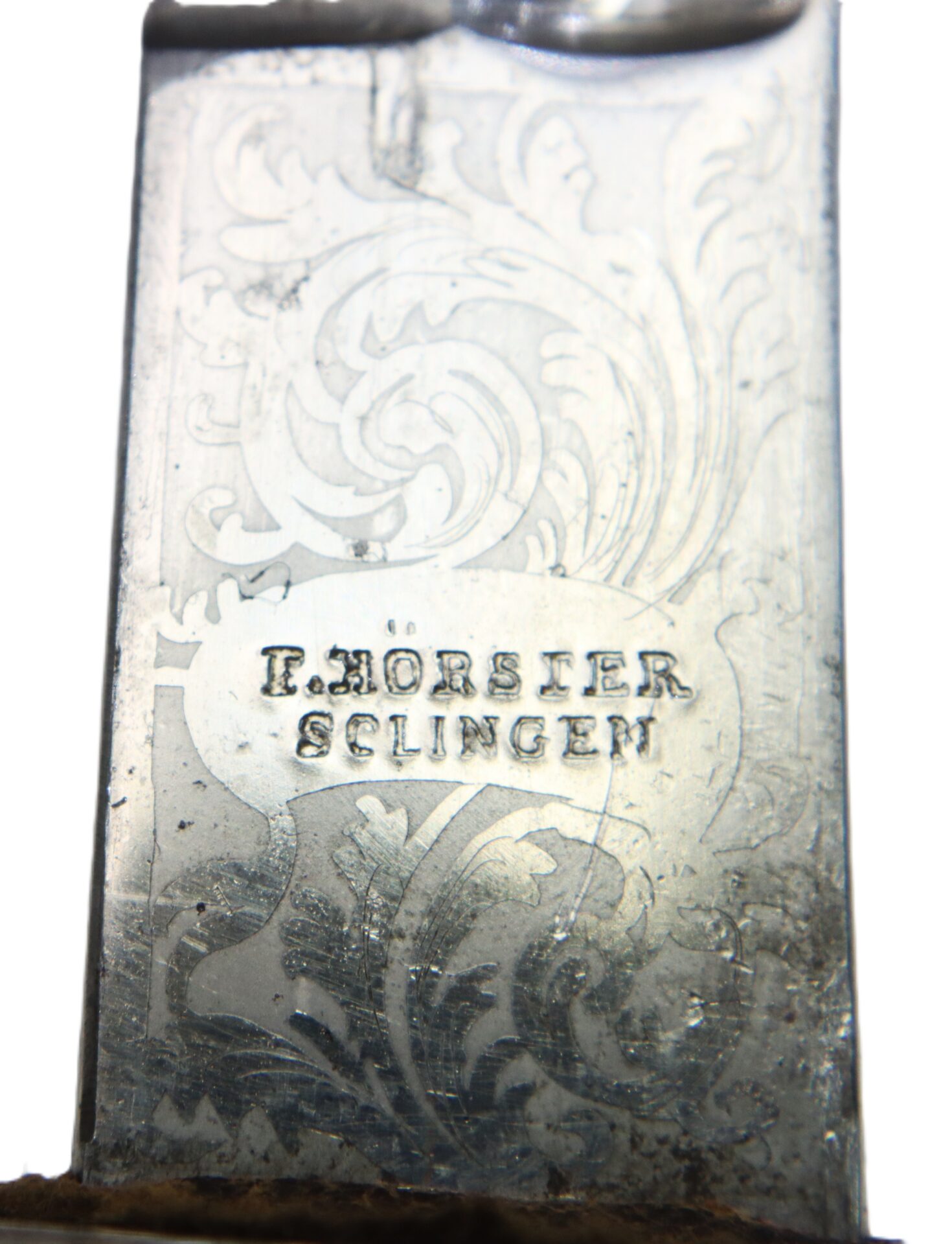 Close-up of an engraved metal blade featuring ornate patterns and the stamped text "F. HORSTER SOLINGEN.
