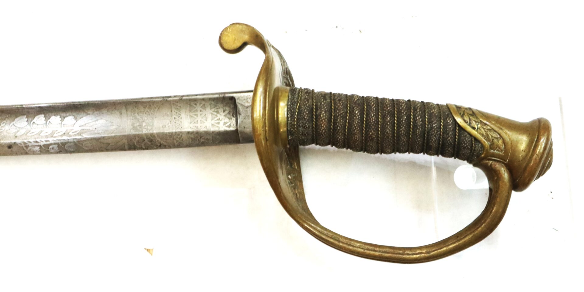 A close-up of an antique sword with an ornate brass guard and a wrapped handle, featuring decorative engravings on the blade.