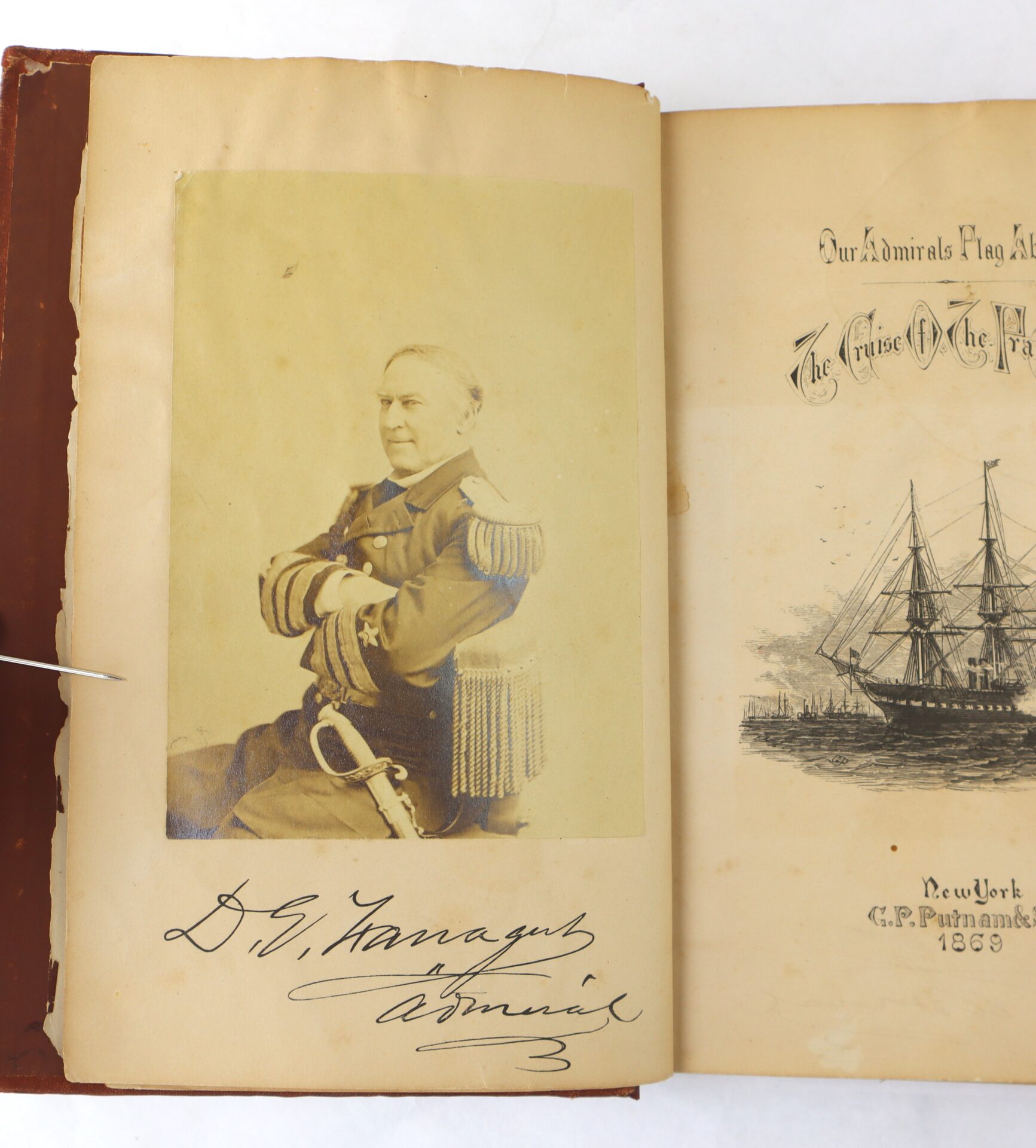 Sepia photograph of a seated man in a naval uniform with epaulettes, next to a book page featuring a ship illustration and the text "Our Admirals Flag" and "1869.