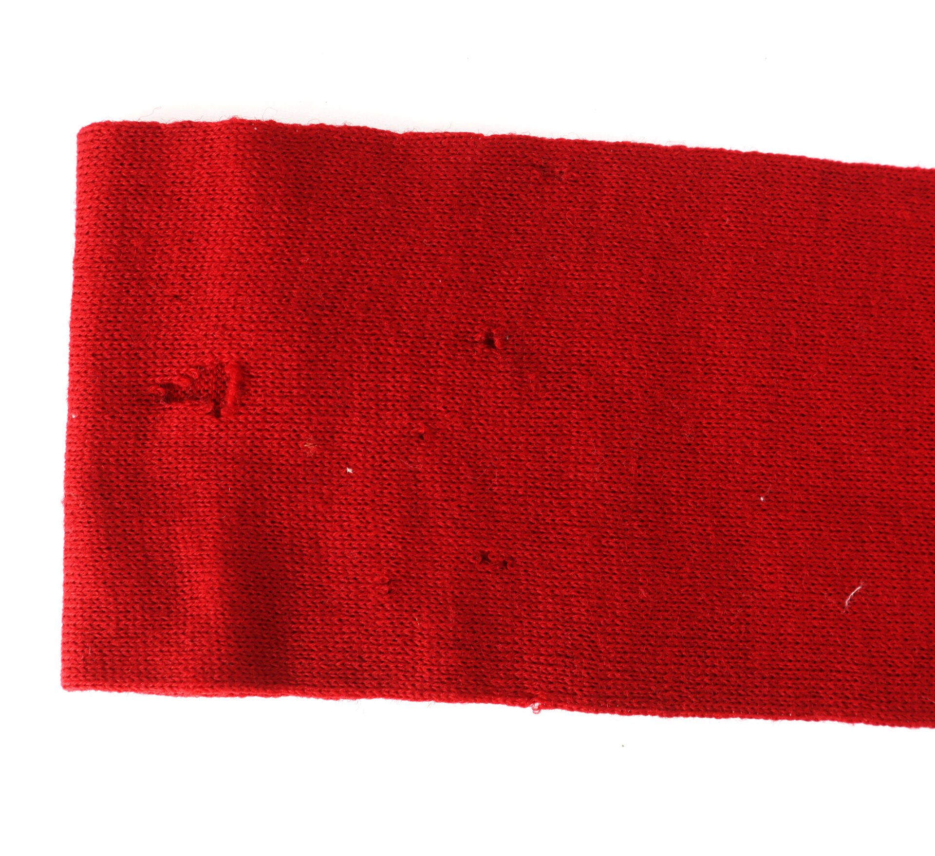A red fabric strip with several small holes and visible signs of wear against a white background.
