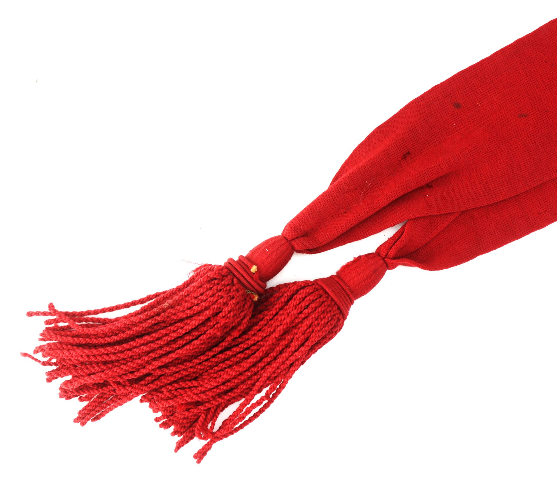 A close-up of a red woven fabric with two tassels tied at the end.