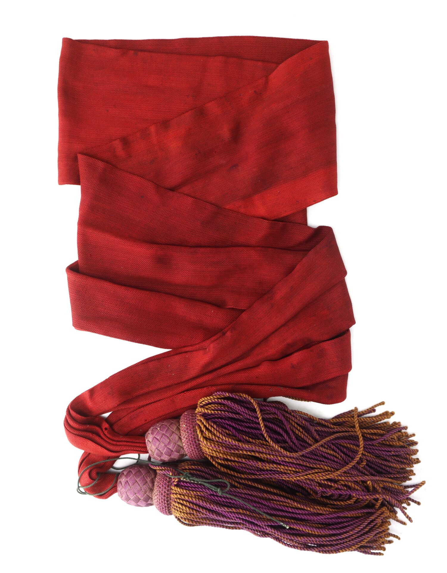 A long red sash with two purple and gold tassels at one end, laid out on a white background.