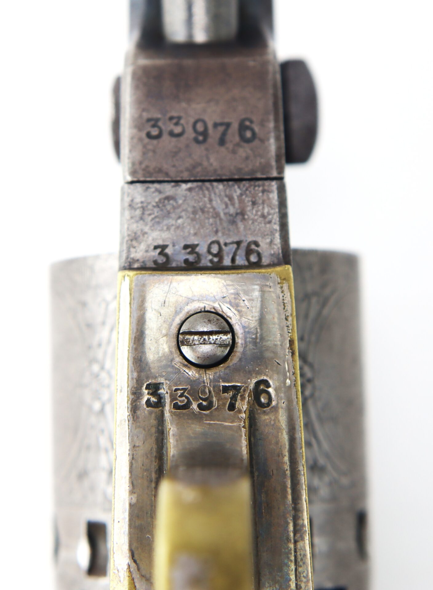 Close-up view of a vintage revolver showing the serial number 33976 stamped on multiple metal parts.