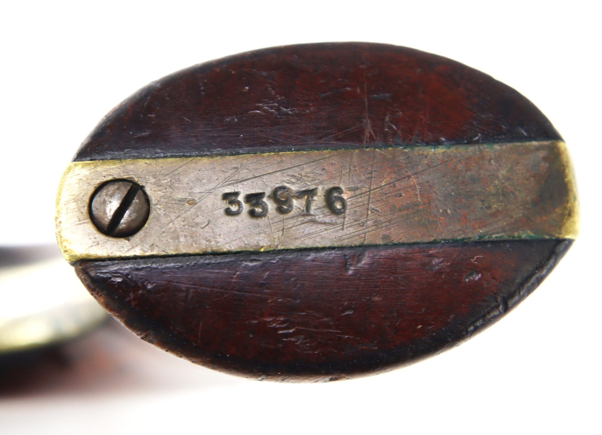Close-up of the base of a wooden object with a brass plate, showing a screw on the left and the number 35876 engraved on the metal.