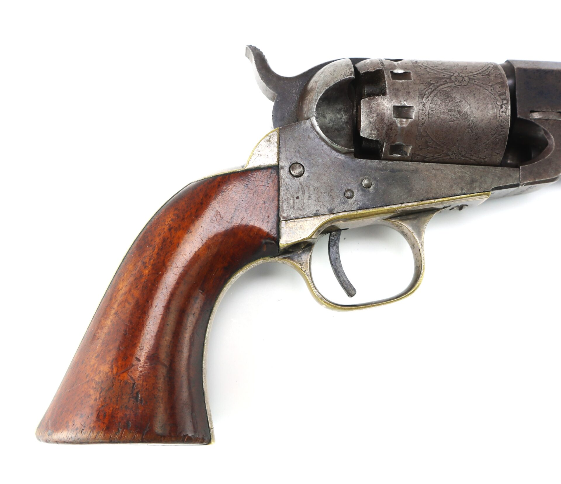 Close-up of the handle and trigger of an antique revolver with a wooden grip and metal frame, showing part of the engraved cylinder.