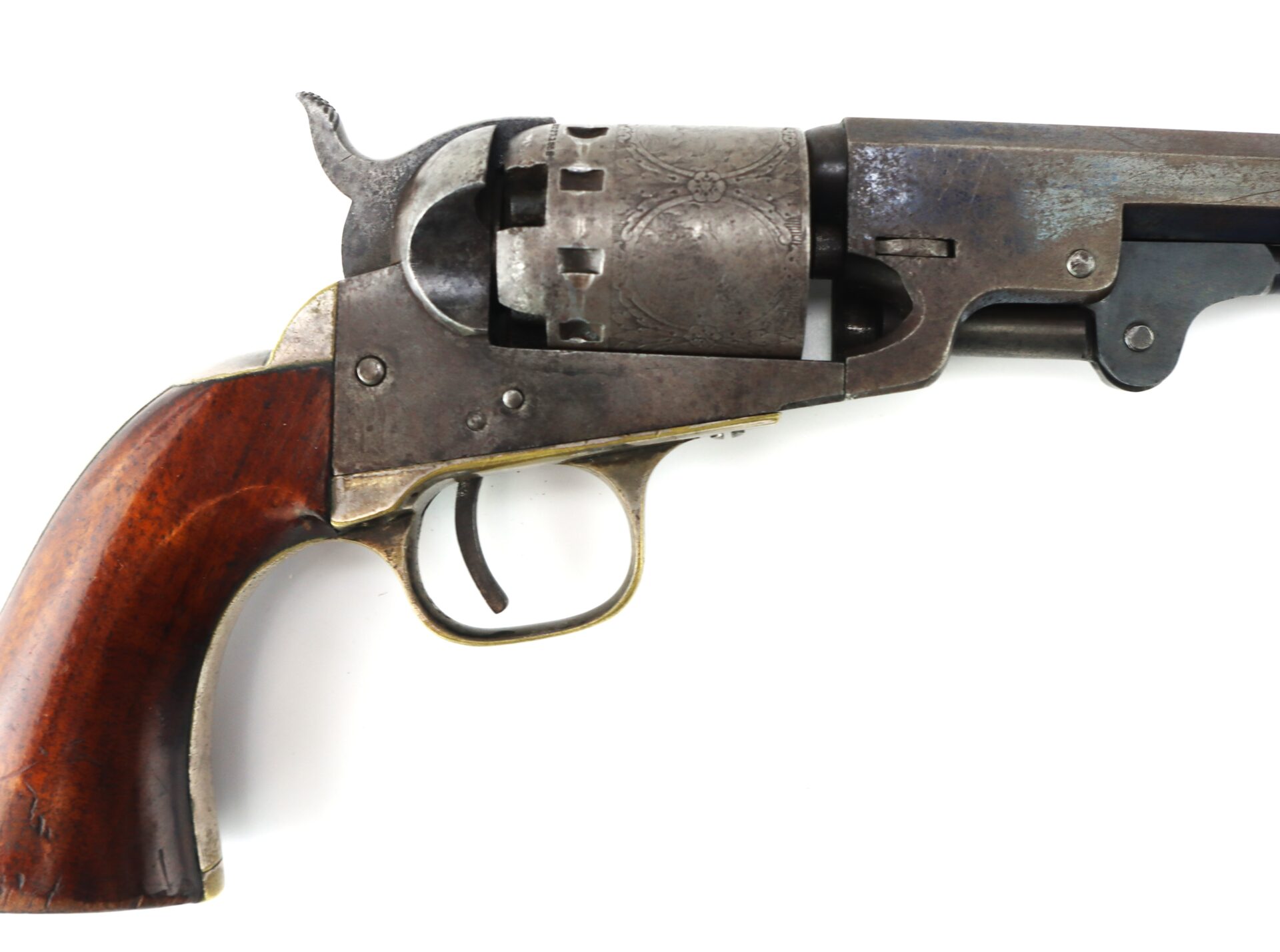 Close-up of an antique revolver with a wooden handle and an engraved metal cylinder, shown against a white background.