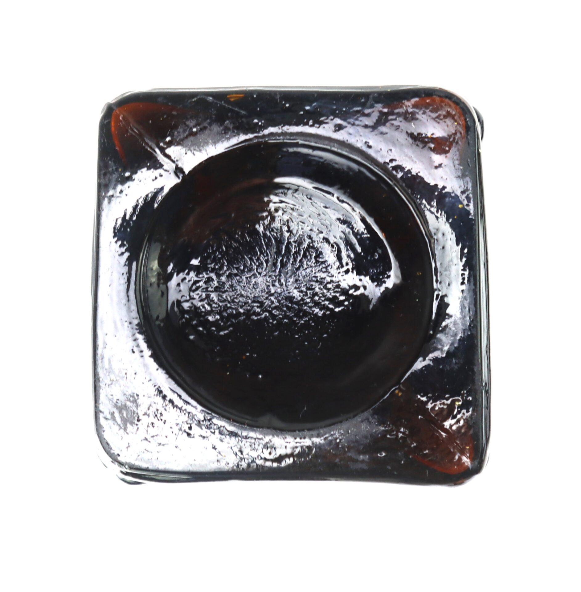A square glass container with a round, dark central area, viewed from above on a white background.
