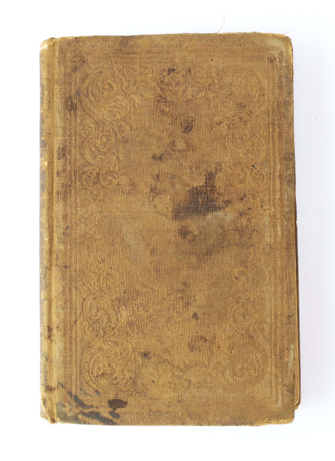 A worn, brown hardcover book with embossed decorative patterns on the cover, showing visible stains and signs of age.