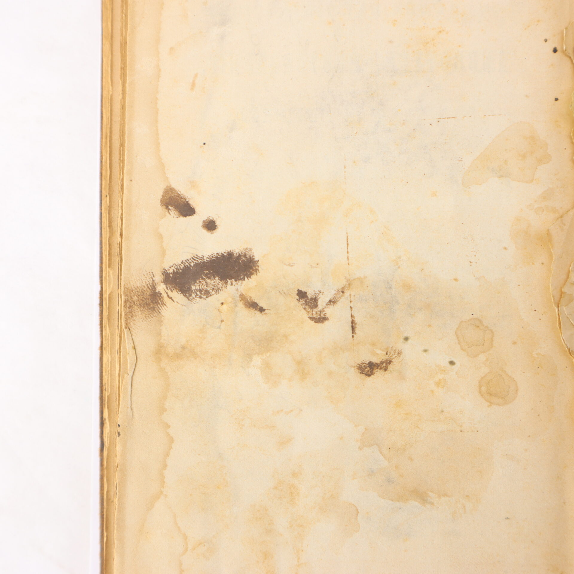 A stained and aged book page with visible water damage, brown marks, and smudges along the left edge.