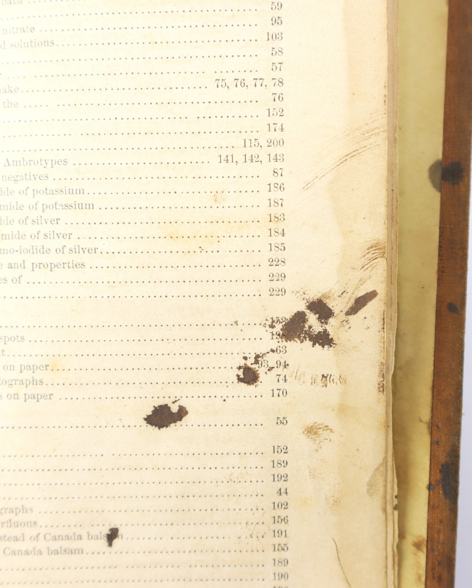A close-up of a stained and partially damaged book page displaying a table of contents with visible ink and water stains on the right side.