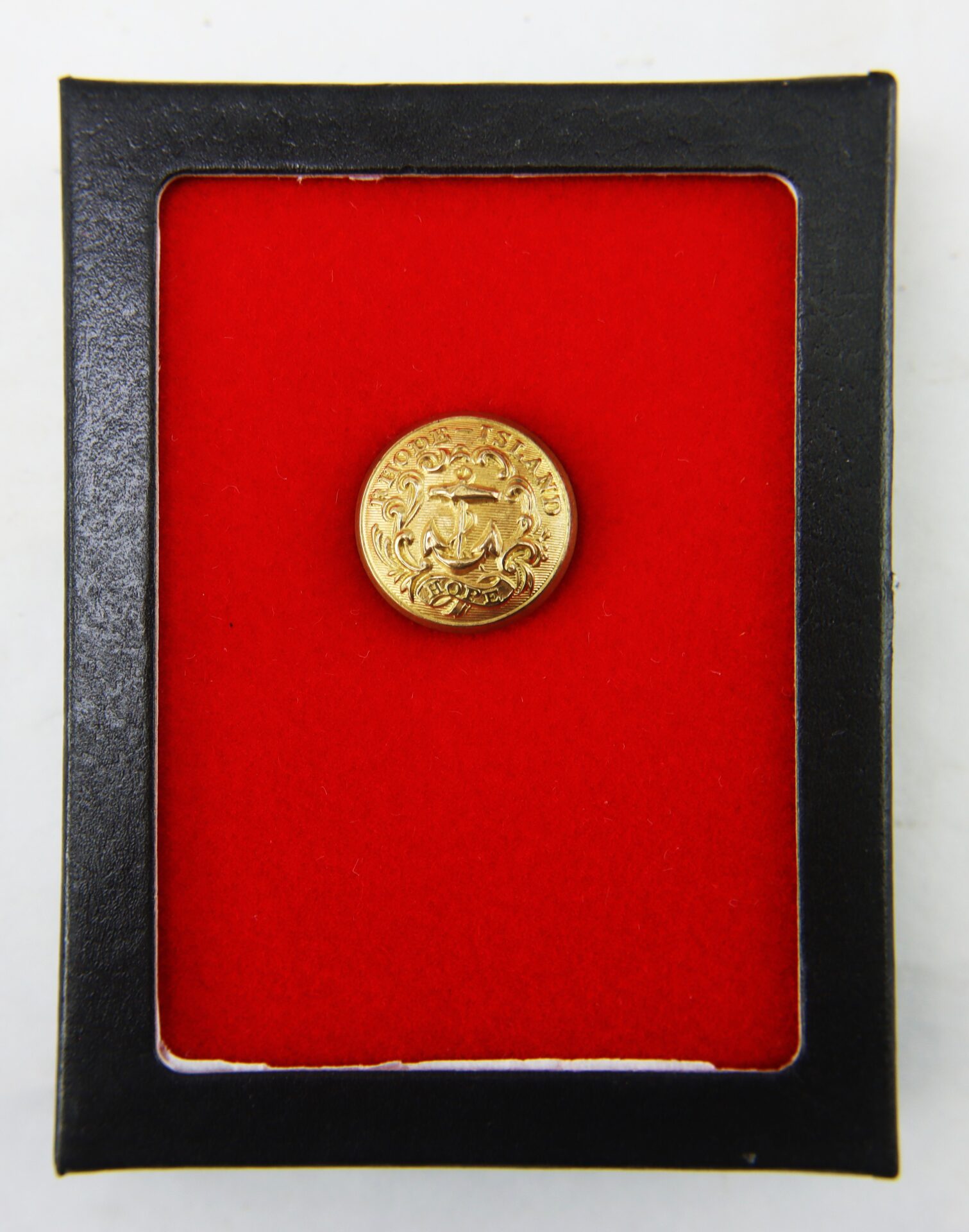 A gold coin displayed in a black frame with a red background. The coin features intricate designs and text around its edge.