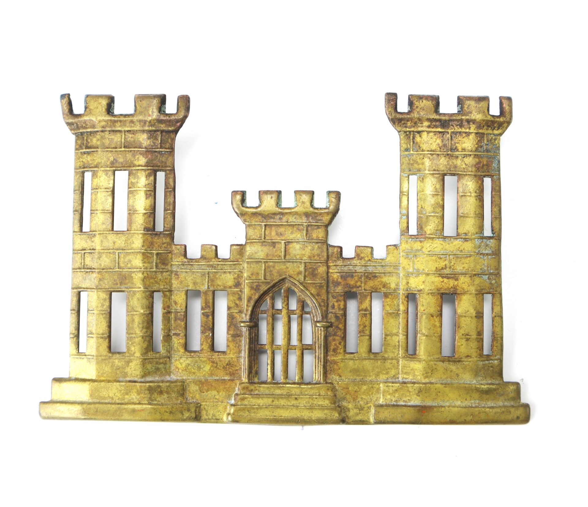 A brass emblem depicting a castle with two towers and a central gate, commonly associated with the U.S. Army Corps of Engineers.