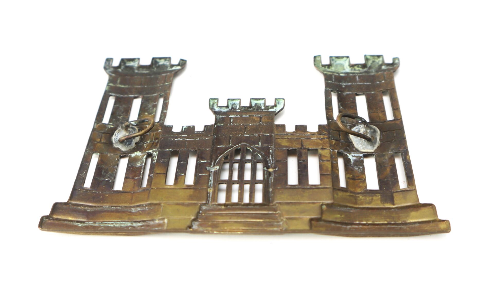 Bronze-colored metal insignia shaped like a castle with three towers and a central gate; typically used for U.S. Army Corps of Engineers uniforms.