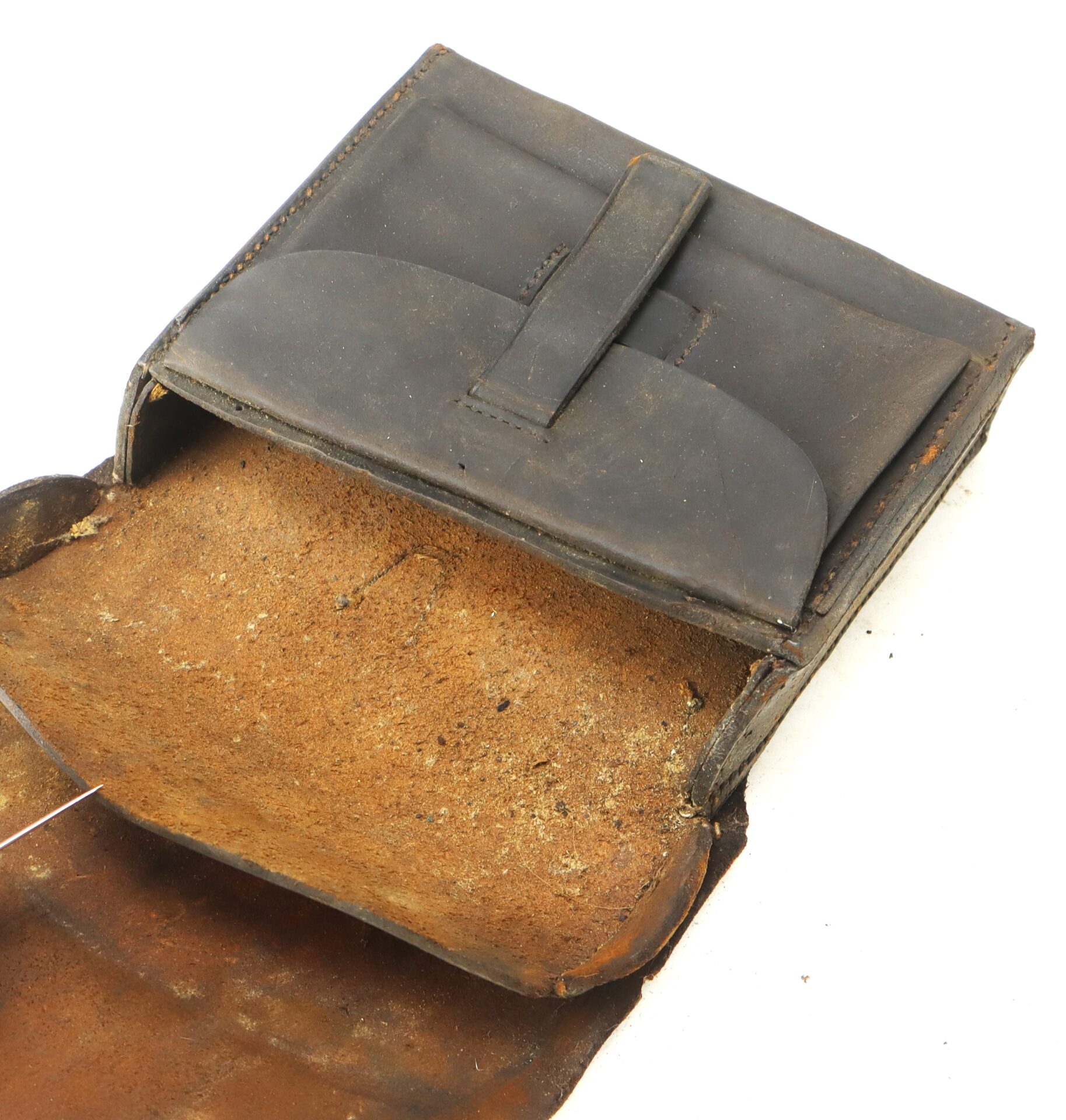 A worn, open leather pouch with a flap, showing its rough interior and a pocket secured by a narrow strap.