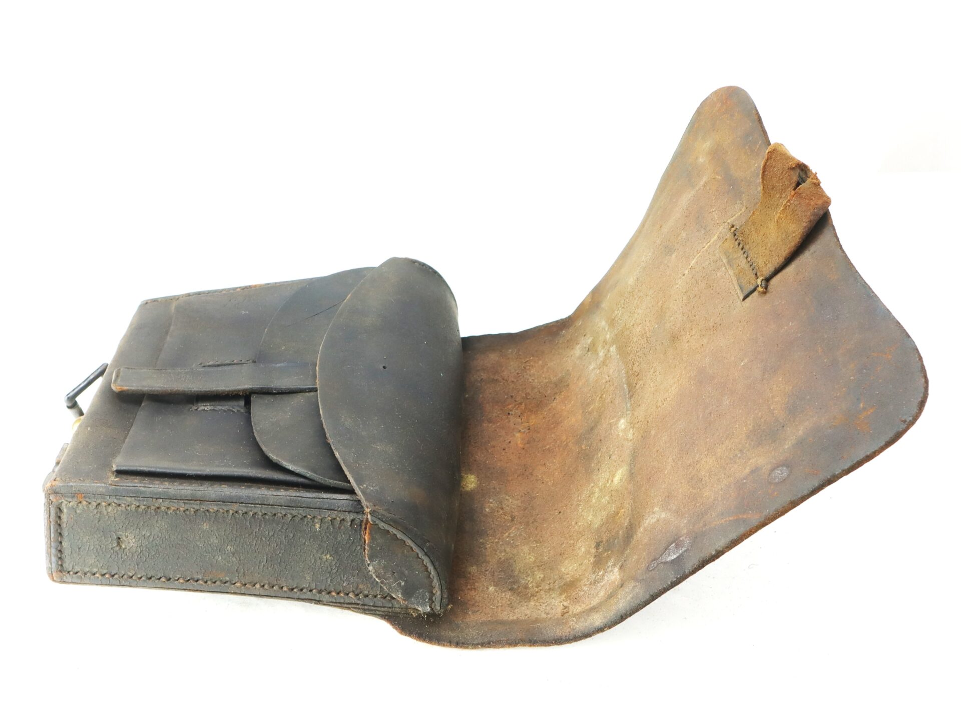 A worn, vintage leather satchel with a flap open, revealing an inner compartment and an attached strap.