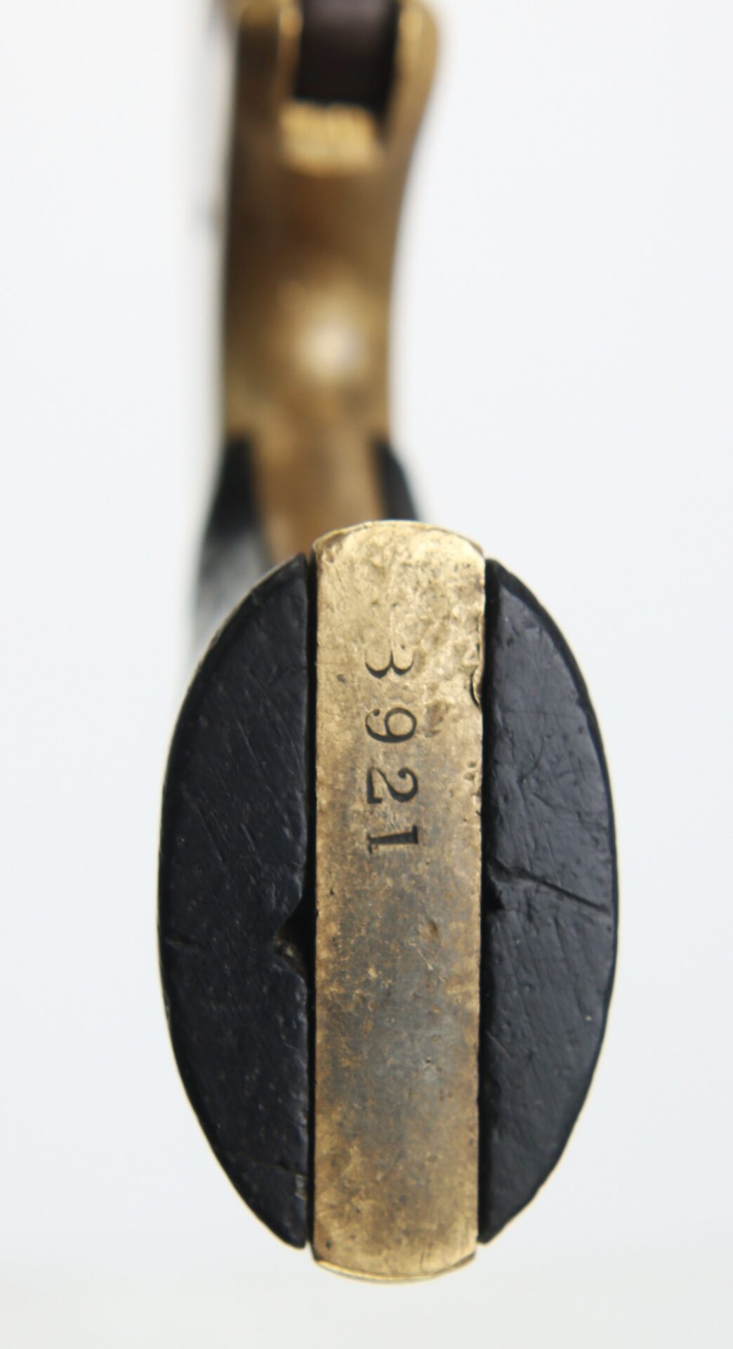 Close-up of the brass and black handle end of an object, showing the engraved number "3921" on the brass section.