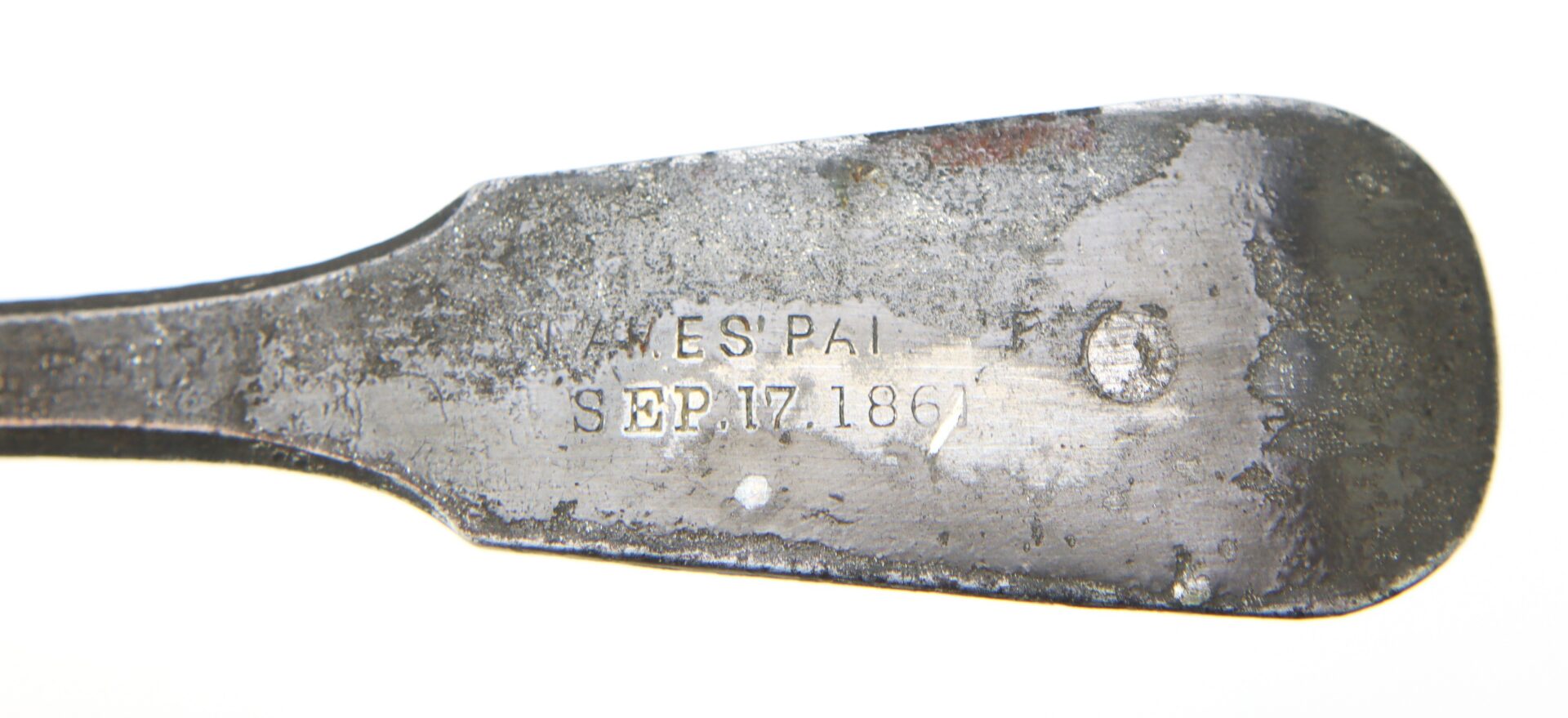 Close-up of a metal object with engraved text reading "SEP. 17. 1861" and partially visible letters "ES PAT." on a tarnished surface.