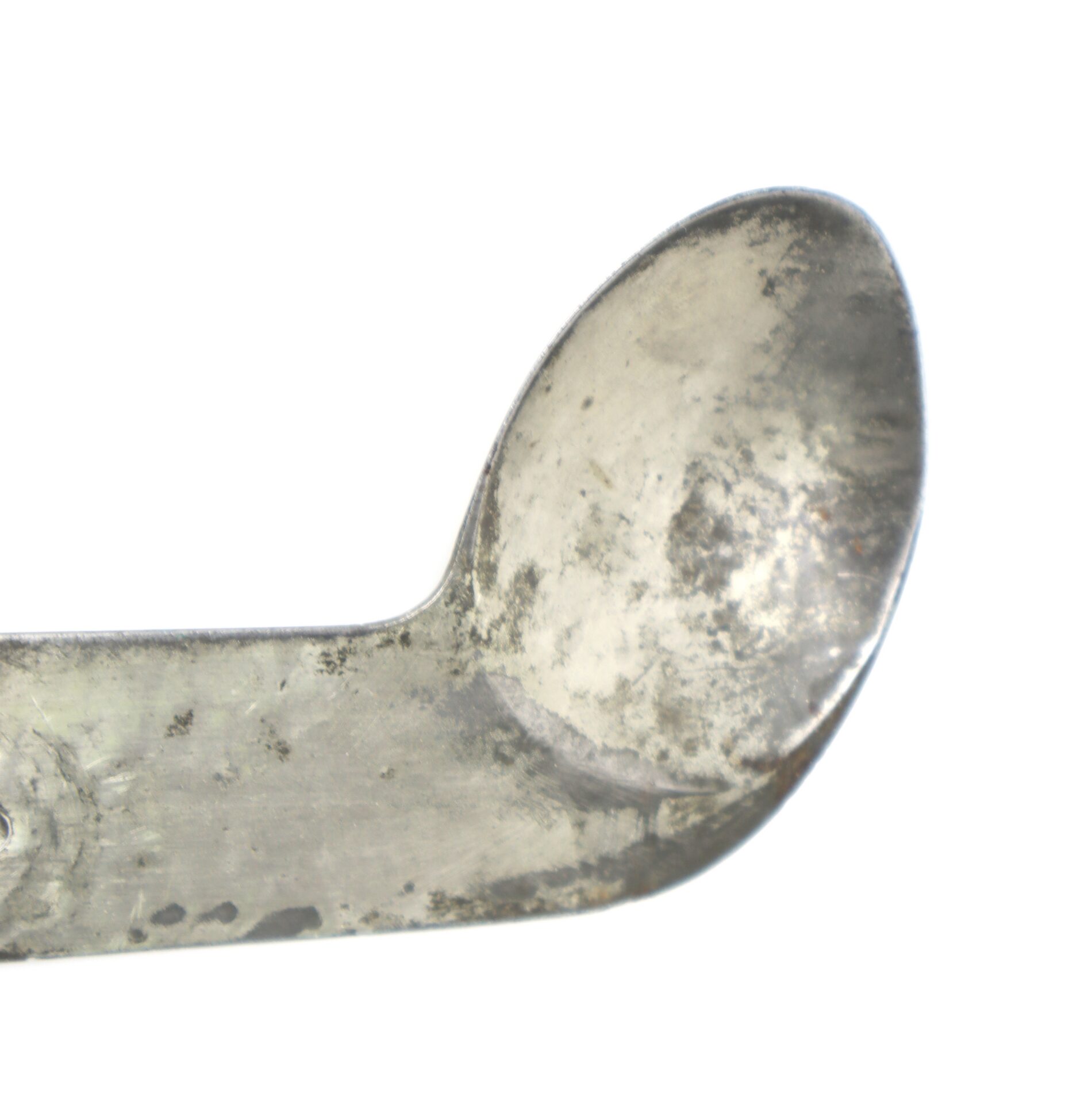 Close-up of a worn, metal spoon with a rounded bowl and visible scratches and discoloration.