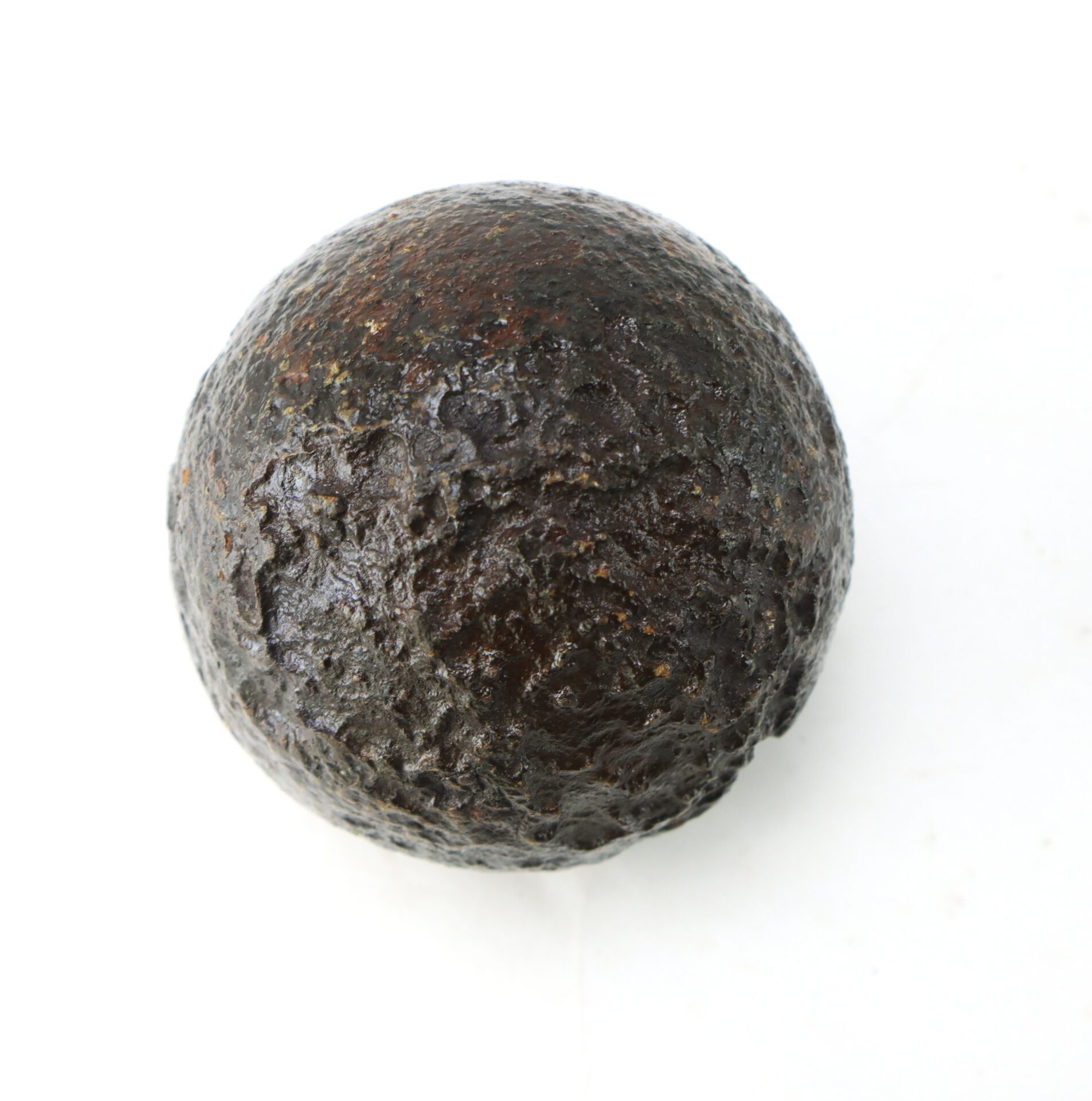 A single round, dark brown object with a rough texture, resembling an aged or weathered cannonball, displayed on a plain white background.