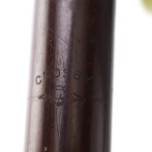 Close-up of a wooden object engraved with the word "CROSBY" and a decorative symbol below it.