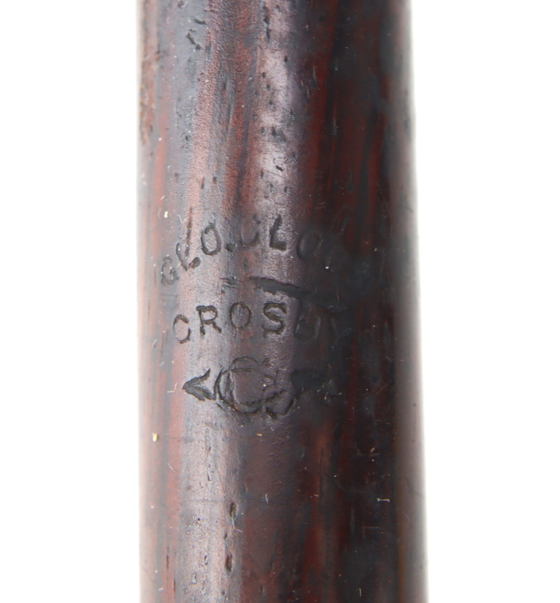 Close-up of dark wooden object with the stamped text "Crosby" and partially visible characters above and below the word.