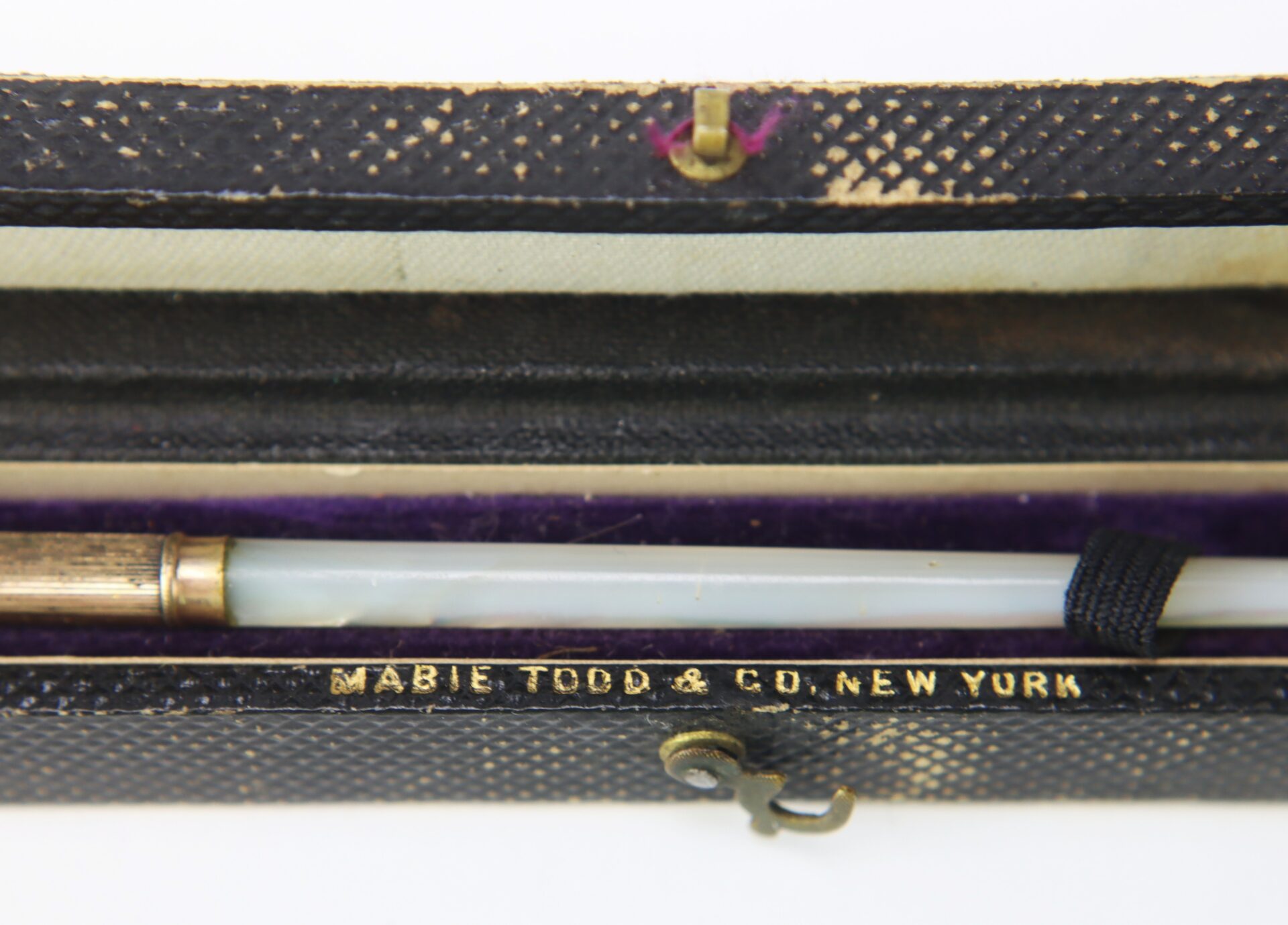 A close-up of a vintage pen in a black textured case, with “MABIE TODD & CO. NEW YORK” embossed in gold on the inside.
