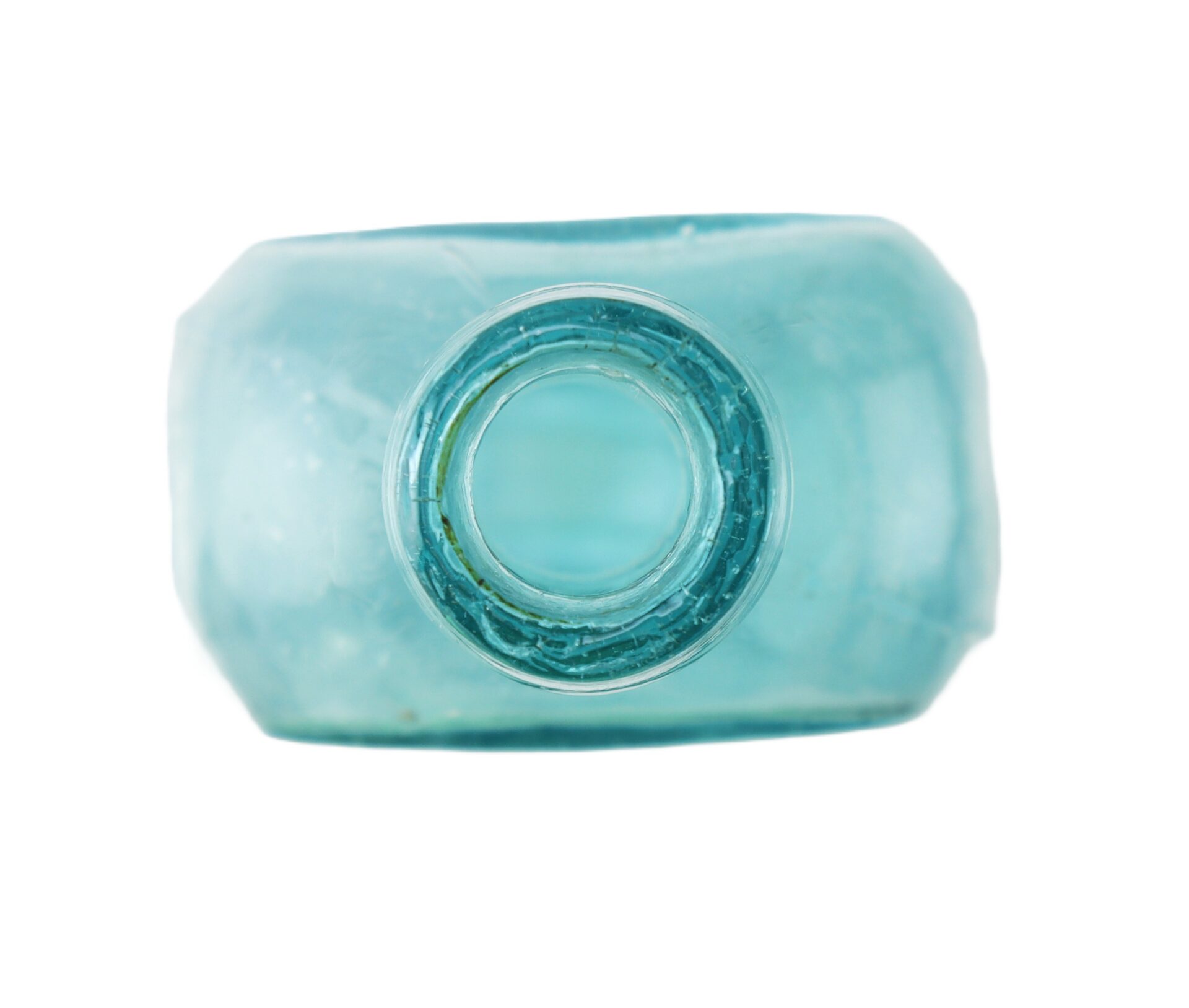 Close-up view of the top of a blue glass bottle, showing the circular opening and thick glass rim against a white background.