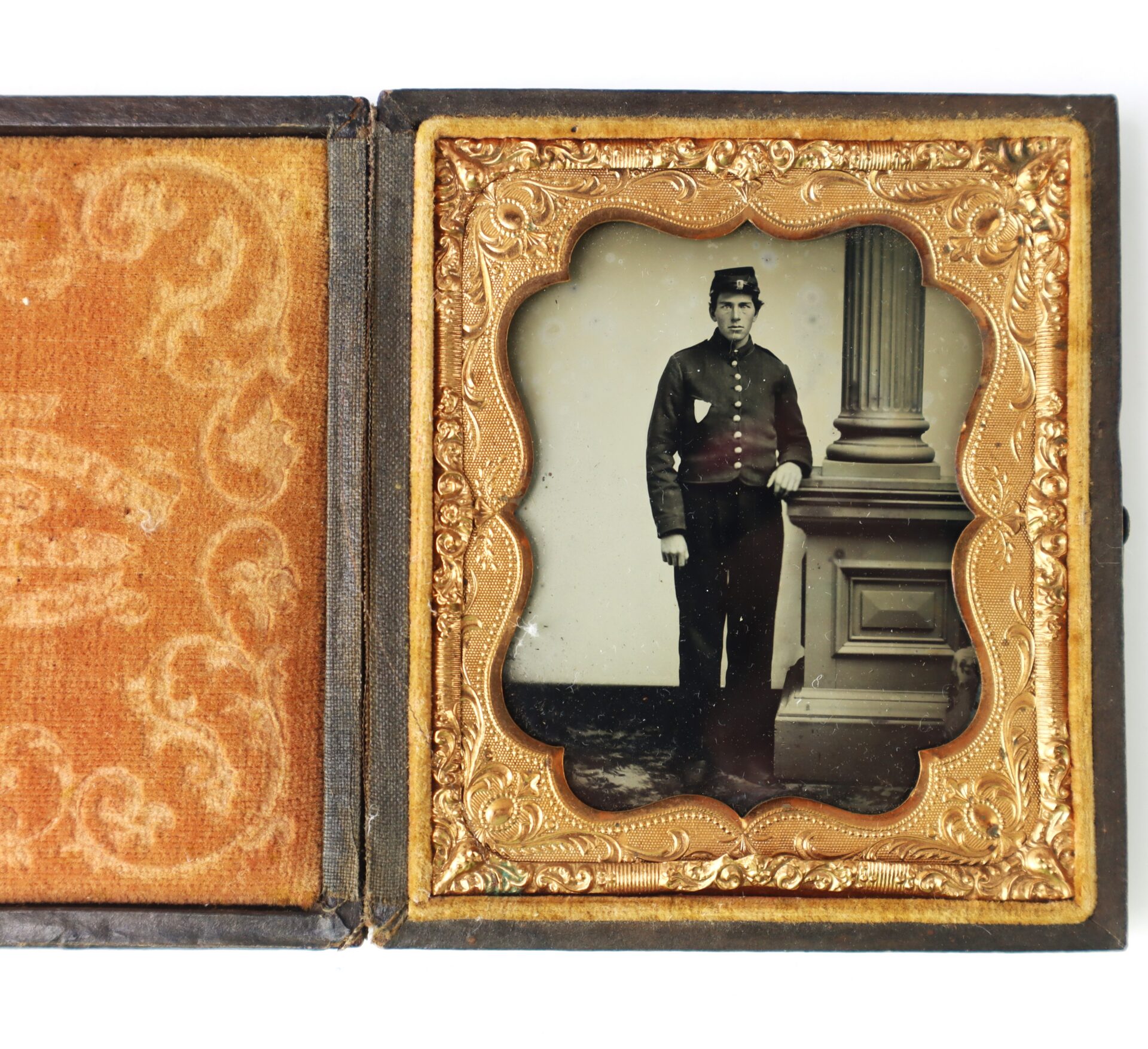 A vintage photograph in an ornate case shows a man in a uniform standing beside a column, with one hand tucked into his jacket.