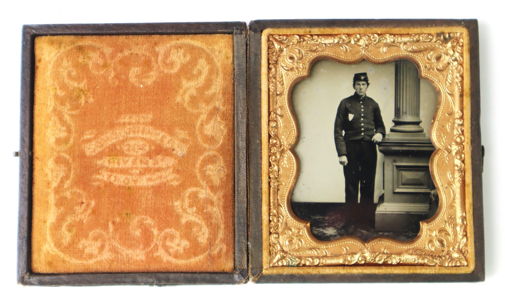 An antique photo case opened to show a portrait of a man in a military uniform standing by a column, with an ornate gold frame around the photograph.