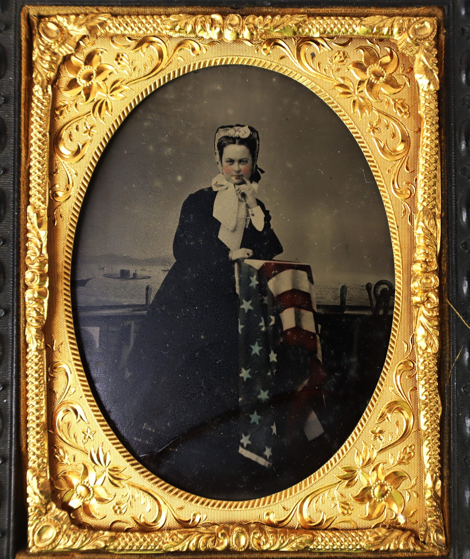 A woman in 19th-century attire poses with an American flag, framed by an ornate gold oval case.
