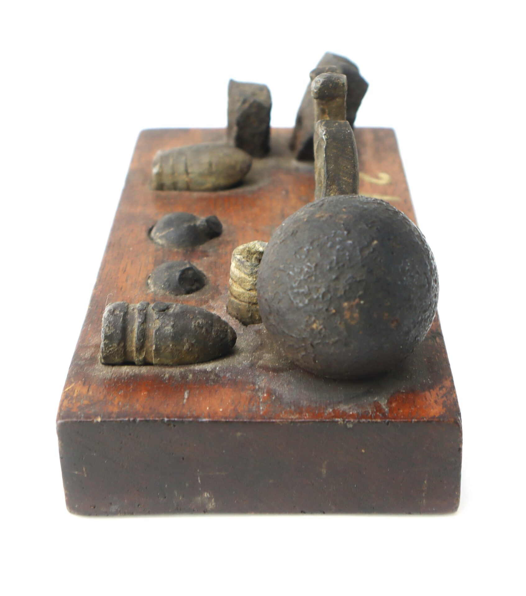A wooden display block holds various historical lead bullets and artillery fragments, arranged in rows.