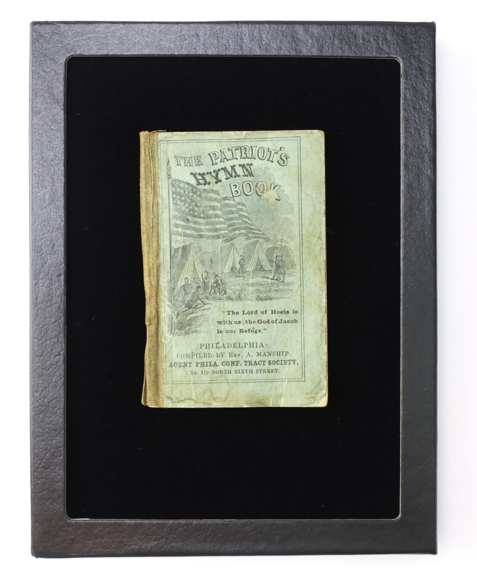 A vintage book titled "The Patriot's Hymn Book" is displayed in a black frame, with an illustrated cover depicting U.S. flags and figures.