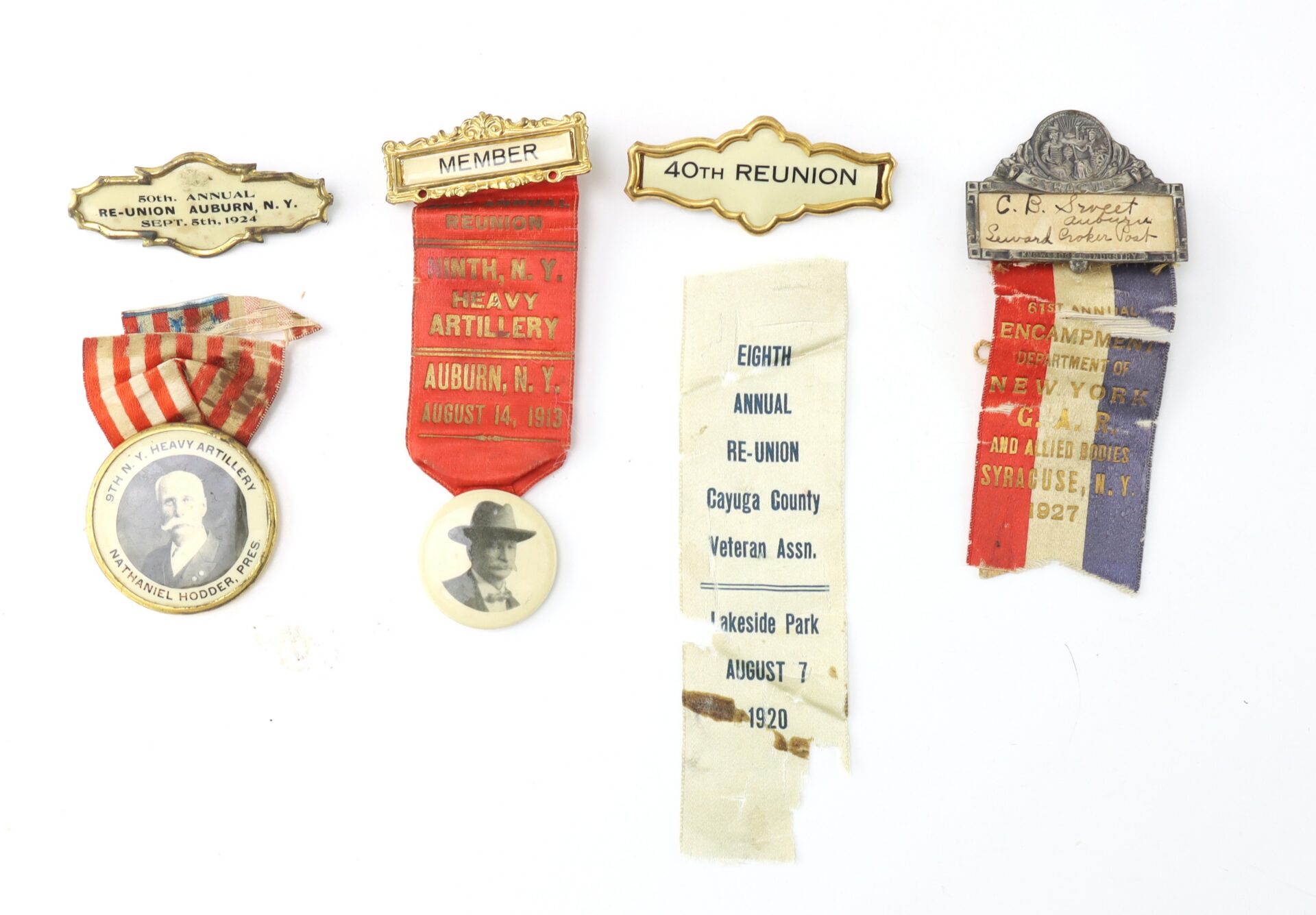 Five vintage reunion badges and ribbons, including portrait pins and text, commemorating artillery veterans' reunions held in New York from the early 1900s to the 1920s.