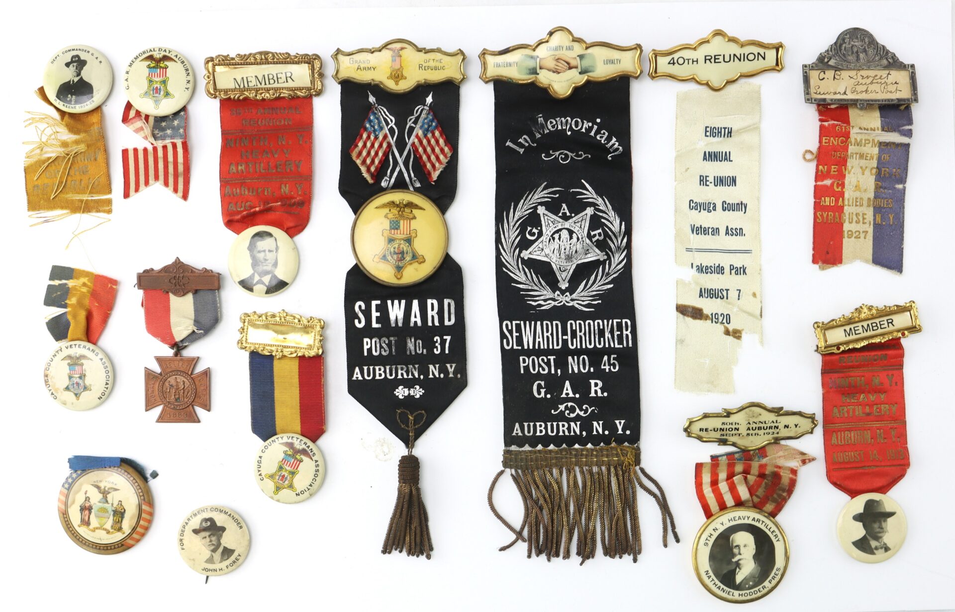 A collection of vintage badges, ribbons, and medals from various veteran organizations and reunions, including items from Seward Post in Auburn, N.Y.